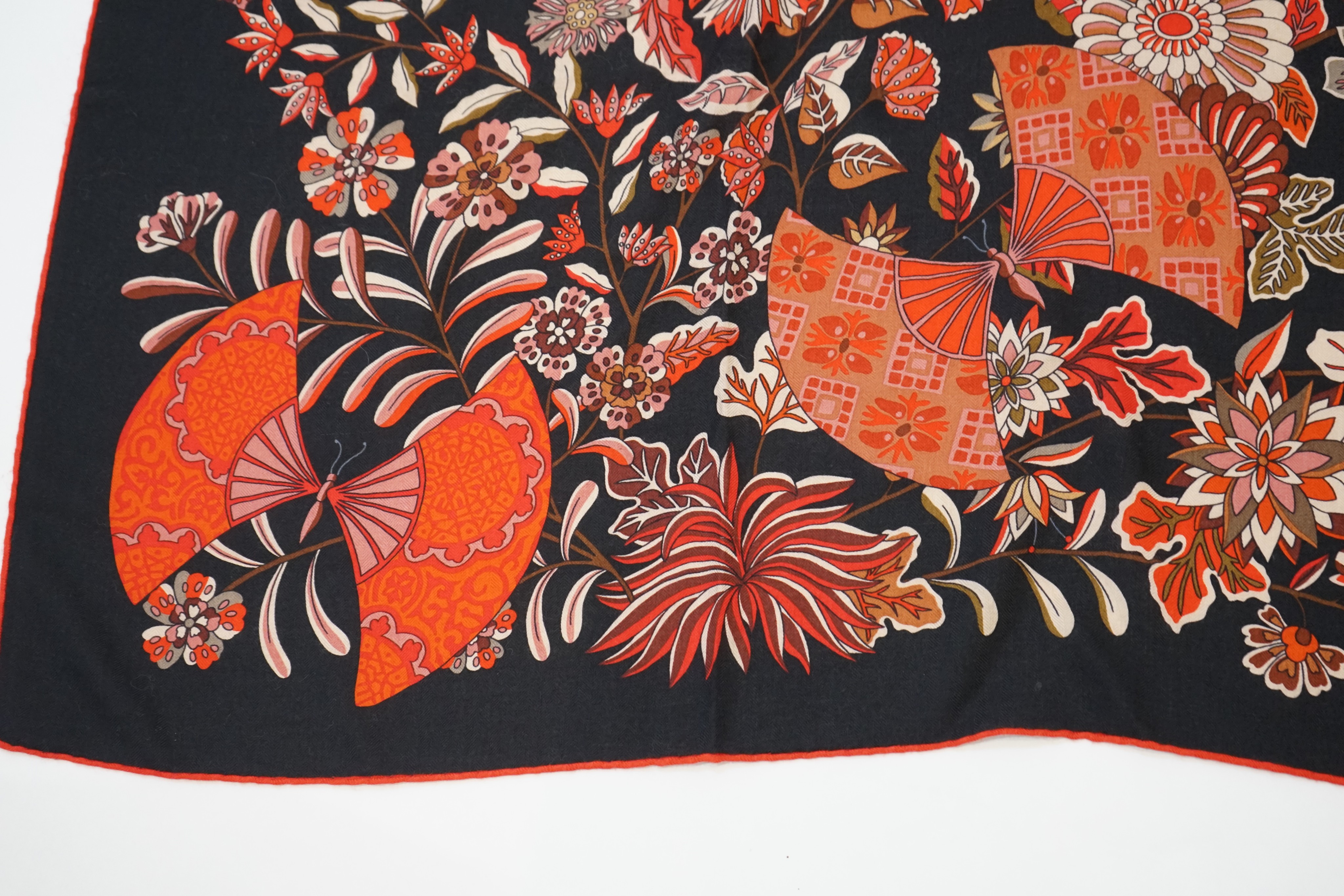 An Hermes wool scarf, with fan and flower motifs on a black ground, in Hermes cloth bag 132 cm.